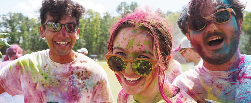 Three students covered in color at Holi Fest.