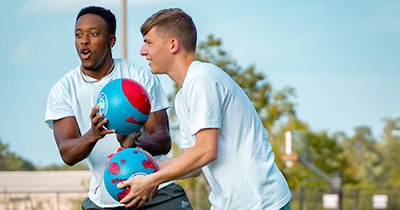 Two students playing sports on campus. 